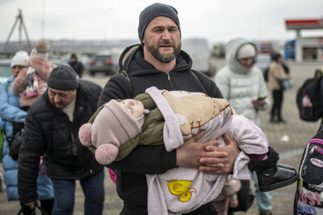 Menekültáradat Ukrajnában. Orosz-ukrán háború elől menekülő férfi gyermekével.